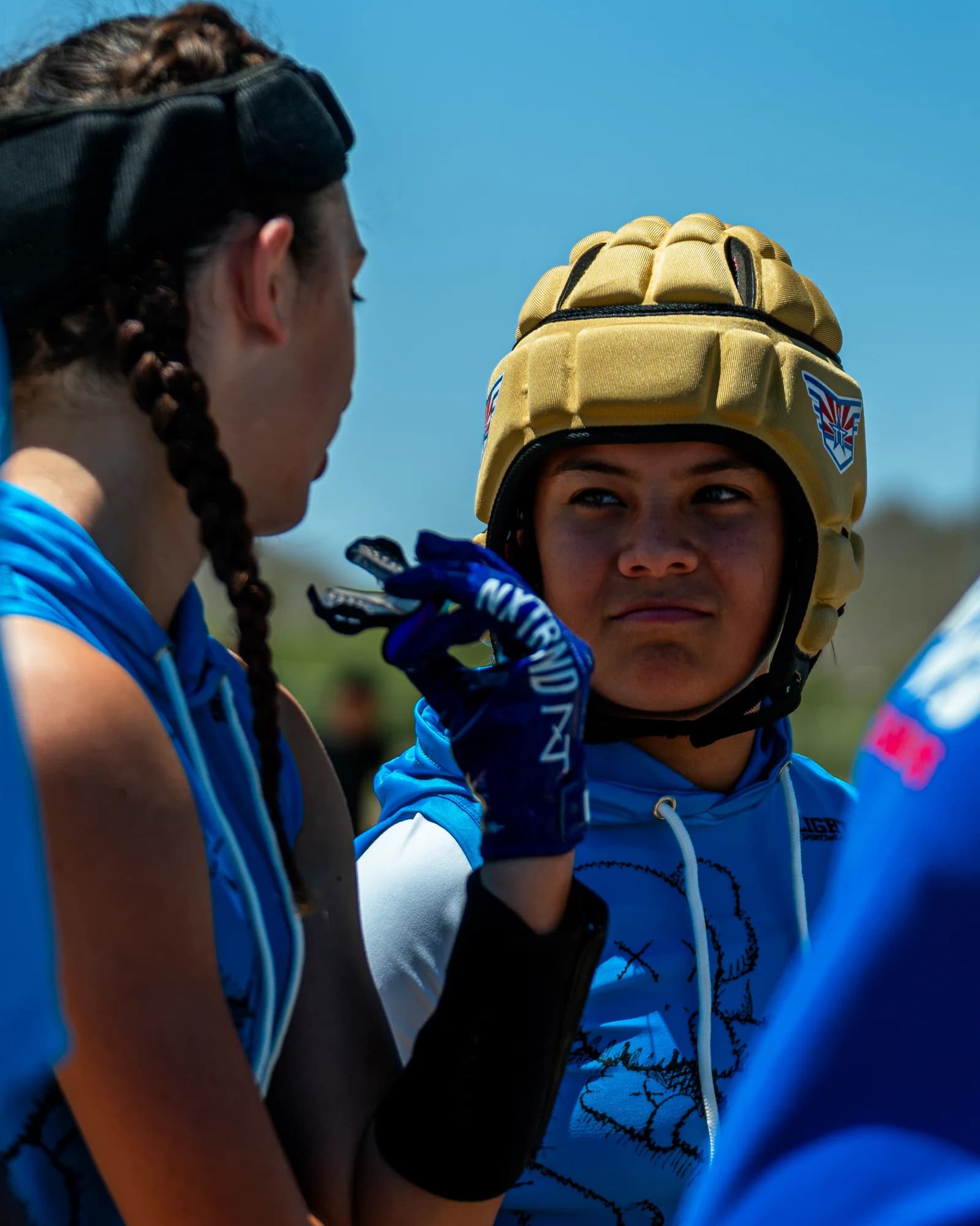Flag football player in game gear listening to a teammate on the sideline