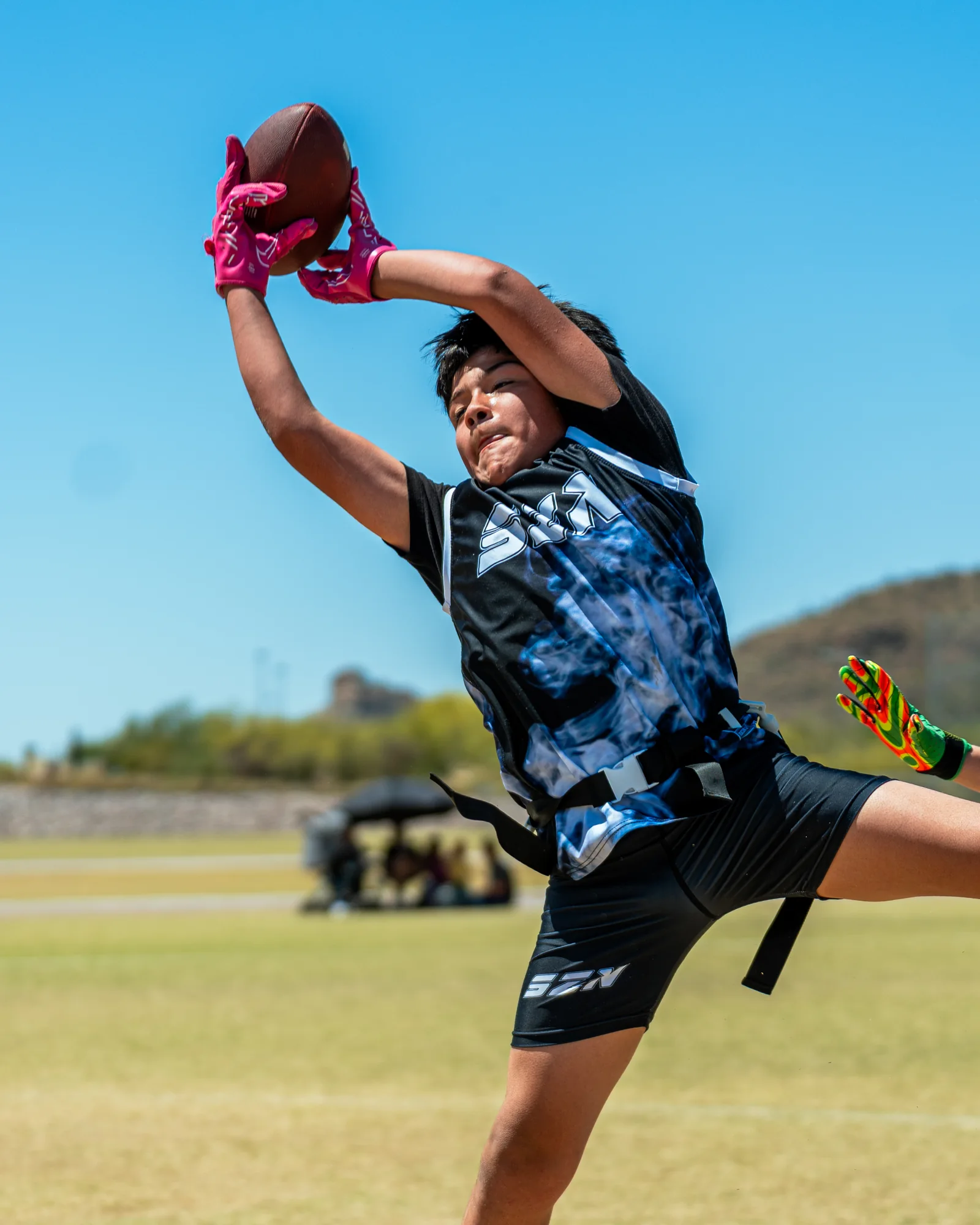 IN SZN athlete securing a high pass against a bright Tucson sky